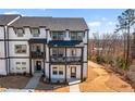 Modern townhome featuring a covered porch and balcony with views of a landscaped lawn at 800 Mackay Crk, Woodstock, GA 30188