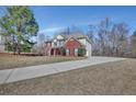 Suburban two-story home showcasing a large driveway, brick accents, vinyl siding and a lush green lawn at 30 Barbara Ct, Fayetteville, GA 30215