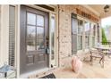 Inviting front door and window with dark shutters, with furniture, and red brick at 3621 Sutters Pond Way, Kennesaw, GA 30152