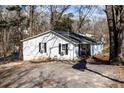 A quaint single-story home with white siding, black shutters, an asphalt driveway, and mature trees at 100 Daisy Cir, Canton, GA 30114