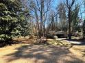 View of backyard and covered parking, surrounded by trees, plants, and a well-maintained grassy lawn at 5169 Oxbow Rd, Stone Mountain, GA 30087