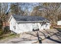 Cozy white home with dark roof, nestled among trees, features a well-maintained exterior and front yard at 70 Daisy Cir, Canton, GA 30114