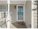 Close up of front door, side window with white trim, decorative exterior light, and grey siding at 826 Shore Dr, Lithonia, GA 30058