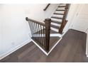 Close-up of a staircase with a dark wood railing and black iron balusters, complemented by sleek wood floors at 516 Healy Dr # 69, Cumming, GA 30040