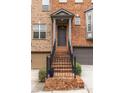 Elegant brick townhome entrance featuring stairs, iron railing, and covered porch at 873 Cedar River Se Ct, Marietta, GA 30067