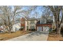 Charming two-story home with a brick and siding facade, green shutters, attached two-car garage, and flowering trees at 5706 Spring Mill Cir, Lithonia, GA 30038