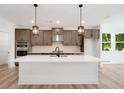 Modern kitchen features a large island with white countertop, stainless steel appliances, and stylish pendant lighting at 1465 Auburn Glen Rd, Dacula, GA 30019