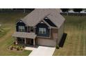 Aerial view of a two-story home with brick and blue siding, well-manicured lawn, and a driveway leading to the garage at 200 Baumgard Way, Locust Grove, GA 30248