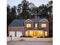 Charming brick home at dusk with a two-car garage and inviting front porch, set against a backdrop of tall trees at 4007 Fellowship Dr, Buford, GA 30519