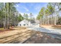 Rear view of the home, complemented by an attached garage, a well manicured yard, and wooded surroundings at 1312 Mcgarity Rd, Temple, GA 30179