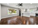Bright living room featuring hardwood floors, a ceiling fan, and large window overlooking the front yard at 2873 Sylvan Rd, East Point, GA 30344