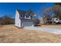 A gray two-story home featuring a two-car garage and long concrete driveway at 7477 Caribou Trl, Riverdale, GA 30296