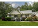 Charming home featuring a metal roof, inviting front porch, landscaping, and a two-car garage with basketball hoop at 281 Laney Dr, Locust Grove, GA 30248