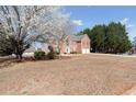 Charming two-story brick home with red shutters and attached two-car garage surrounded by trees and grass at 6844 Cavalier Ct, Stone Mountain, GA 30087