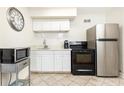 Efficient kitchen featuring black appliances, white cabinetry, and neutral tile flooring at 300 W Peachtree St # 8C, Atlanta, GA 30308