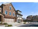 View of the townhome exteriors displaying the stone facade, arched entry, and manicured lawn at 202 Via Lucca, Woodstock, GA 30188