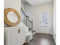 Bright and inviting foyer with hardwood floors, white cabinet, round mirror and staircase at 1566 Ridgebrook Downs, Mableton, GA 30126