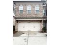Two-car garage boasts white doors and a brick facade for added curb appeal at 2021 Towneship Trl, Roswell, GA 30075