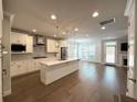 Bright, open kitchen features white cabinets, island with sink, stainless steel appliances, and hardwood floors at 2021 Towneship Trl, Roswell, GA 30075