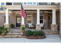 Charming front porch with stone columns, rocking chairs, and an American flag accenting the brick facade at 6880 Nantucket Cv, Cumming, GA 30041