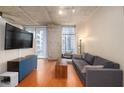 Modern living room with concrete ceiling, hardwood floors, large windows, and comfortable seating at 855 Peachtree Ne St # 1911, Atlanta, GA 30308