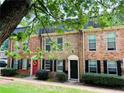 Traditional brick townhome with a red front door and manicured lawn at 235 Winding River Dr # B, Atlanta, GA 30350