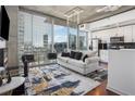 Bright open-concept living area featuring hardwood floors, modern furnishings, and a city view through large windows at 3324 Peachtree Ne Rd # 1115, Atlanta, GA 30326