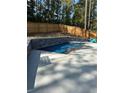 Sparkling in-ground pool with a stone retaining wall and a wooden fence, set in a private backyard with mature trees at 6045 Crowley Dr, Douglasville, GA 30135