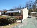 View of tan home featuring a car port, awnings, brick detail, and mature foliage at 2422 Clarissa Nw Dr, Atlanta, GA 30318