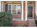 Inviting brick front porch with white columns, black shutters and a freshly painted black front door at 4790 Maristone Landing Way, Cumming, GA 30040