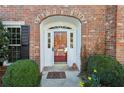 Arched entryway with glass paned door and sidelights framed by blooming spring flowers and dark shutters at 7 Newport Nw Pl, Atlanta, GA 30318