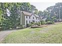 Lovely two-story white home with a well-manicured lawn and mature trees in background at 1590 Greyson Rdg, Marietta, GA 30062