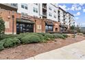 Commercial spaces on the ground floor with awnings, landscaping, and brick facade beneath apartments at 901 Abernathy Ne Rd, Sandy Springs, GA 30328