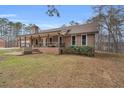 Quaint brick home showcasing a covered porch, manicured lawn, and a serene, tree-lined backdrop at 6890 Cedar Mountain Rd, Douglasville, GA 30134