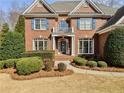 Close up of classic red brick home featuring a covered front porch with meticulously trimmed hedges and lawn at 1320 Kildare Ct, Snellville, GA 30078