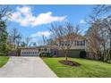 Attractive house with a long driveway, lush green grass, and a beautiful shade tree at 260 Mansell Cir, Roswell, GA 30075