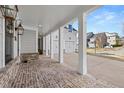 Inviting covered porch with brick flooring, white columns, and elegant lighting fixtures at 1005 Coleman Place Dr, Roswell, GA 30075