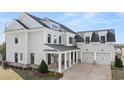 Rear exterior of a two-story home with a spacious three car garage and charming covered porch at 1005 Coleman Place Dr, Roswell, GA 30075