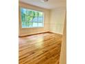 Bedroom with large window providing a natural view, wainscoting, and gleaming hardwood floors at 5531 Four Winds Sw Dr, Lilburn, GA 30047