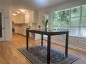 Bright kitchen with white cabinets, stone backsplash, and hardwood floors, dining area with large windows overlooking a wooded view at 5531 Four Winds Sw Dr, Lilburn, GA 30047