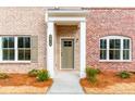 Close-up of the brick home's front entrance with white trim, a stylish door, and manicured landscaping at 4818 Floydwood Ln, Mableton, GA 30126