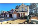 Two-story townhome featuring a brick and yellow exterior, attached garage, and well-kept lawn at 553 Rockbridge Trl, Stone Mountain, GA 30083