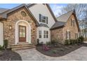 Detailed front exterior showcasing stone accents, a wooden door, stone steps and landscaped garden beds at 2410 Glade Overlook, Cumming, GA 30041