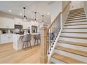 Bright kitchen and staircase with white cabinets, stainless appliances, modern lighting, and hardwood floors at 3340 Cranston Ln, Kennesaw, GA 30144