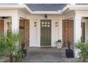 Beautiful brick home entrance featuring an olive-green door, white columns, and manicured plants at 755 Adair Ne Ave, Atlanta, GA 30306