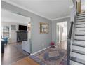 Hallway with grey walls leading to the living room with a fireplace, and staircase with a dark wood handrail at 526 Lakeside Dr, Hiram, GA 30141