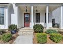 Inviting front porch with brick steps, white columns, and stylish hanging lanterns at 1043 Harvest Park Ln, Suwanee, GA 30024