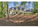 Elegant white brick home with dormer windows and a mature tree covered yard in a residential neighborhood at 1025 Dawn View Nw Ln, Atlanta, GA 30327