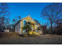 Two-story yellow home with a well-manicured lawn and large trees in a quiet neighborhood at 4558 Bronte Ln, Douglasville, GA 30135