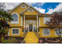 Two-story home featuring a bright yellow exterior with a covered porch, landscaped yard, and blue sky at 4558 Bronte Ln, Douglasville, GA 30135